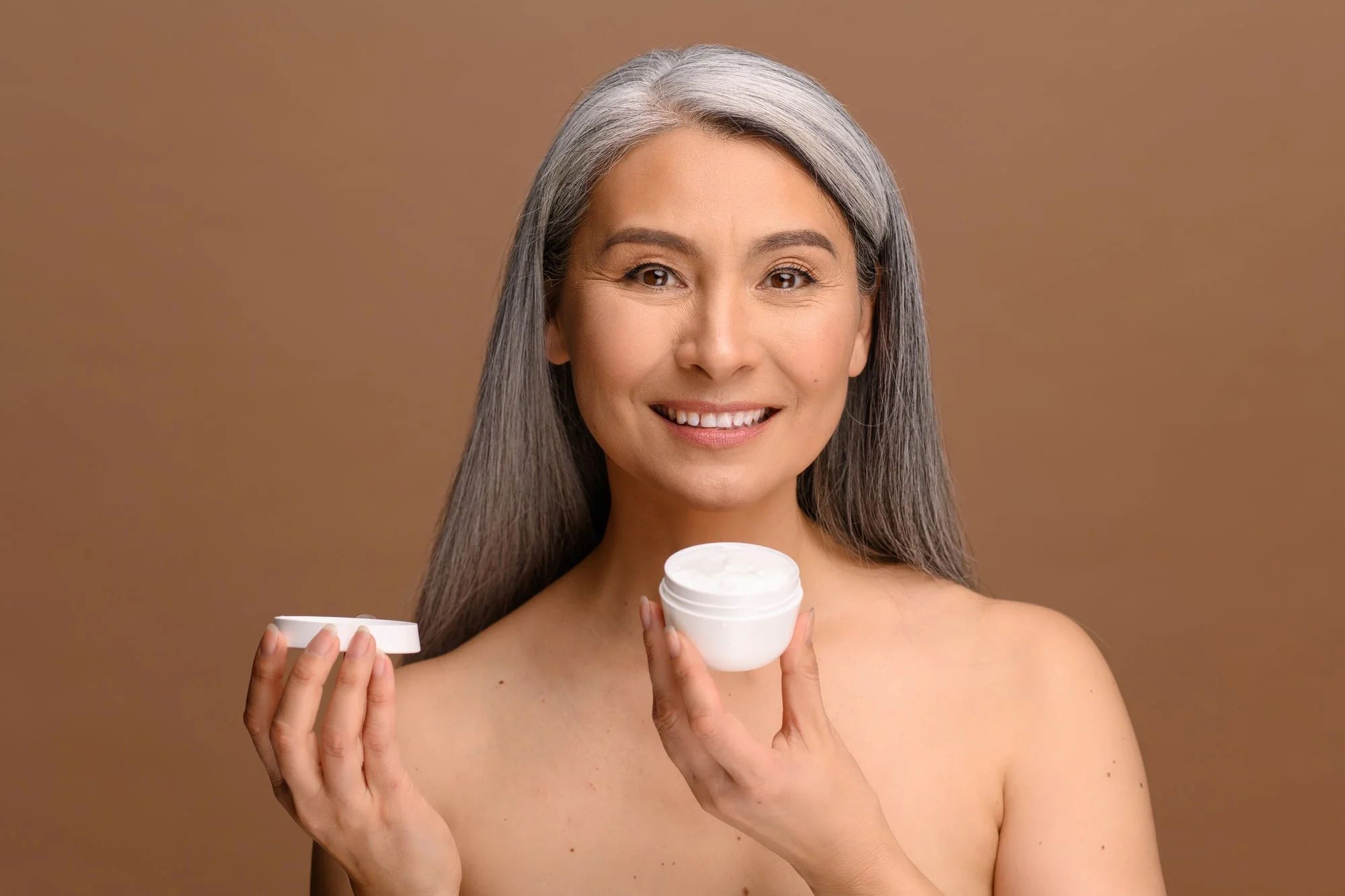 Mature women holding skincare product
