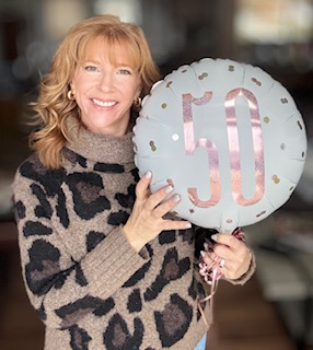 Smiling holding a 50 balloon